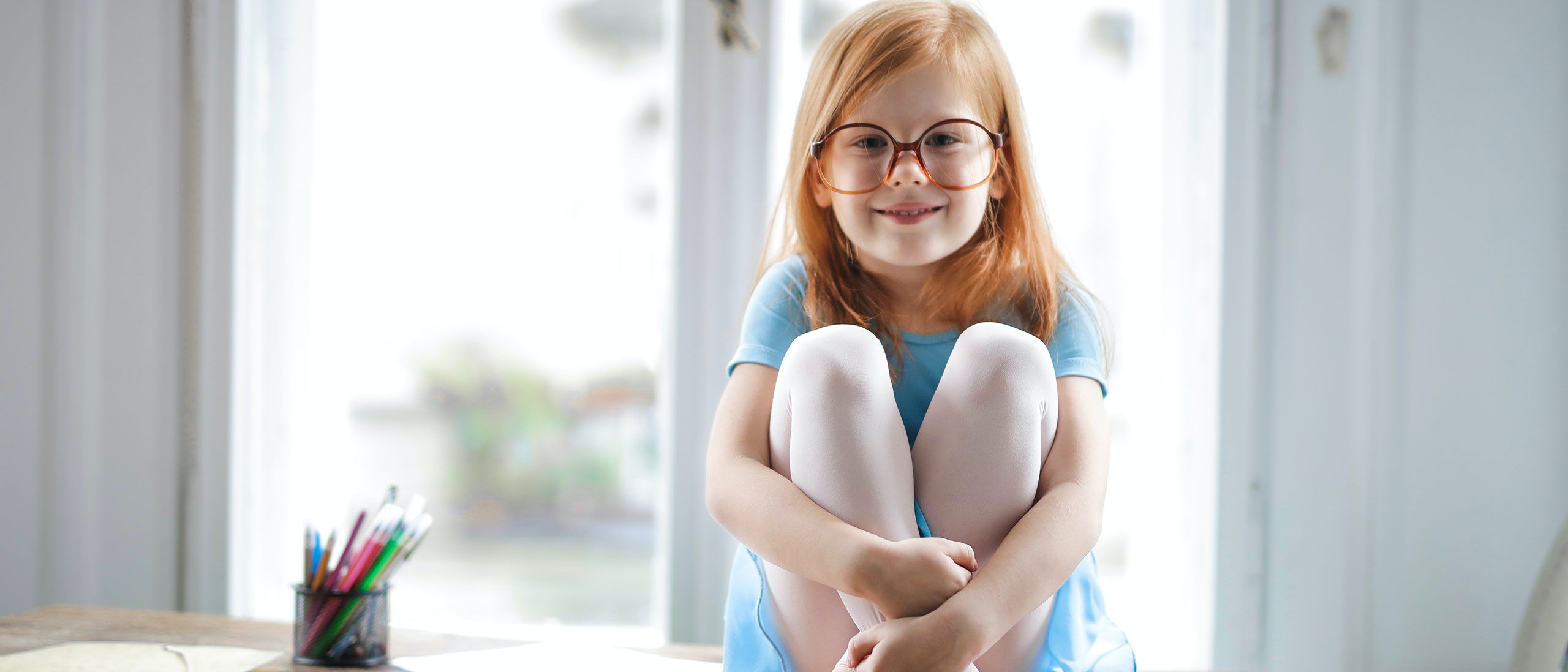 Girl with glasses sitting Niña sentada en un centro de salud mental para niños.